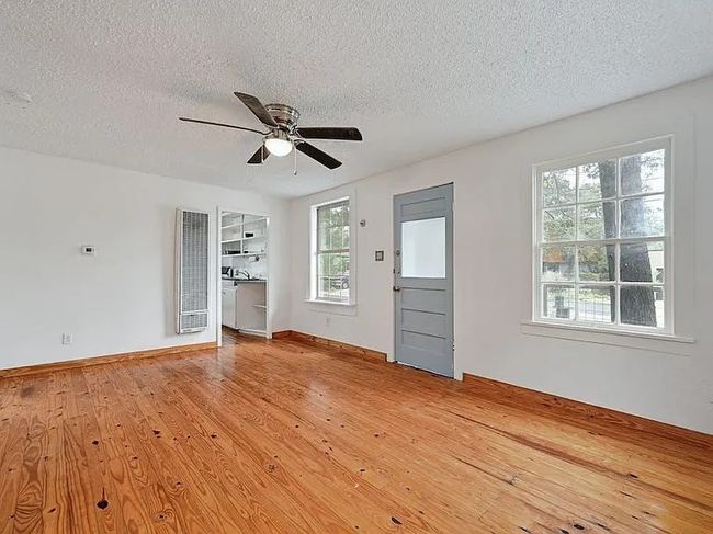 Unfurnished living room with a heating unit, a textured ceiling, a ceiling fan, and light wood finished floors | Image 7