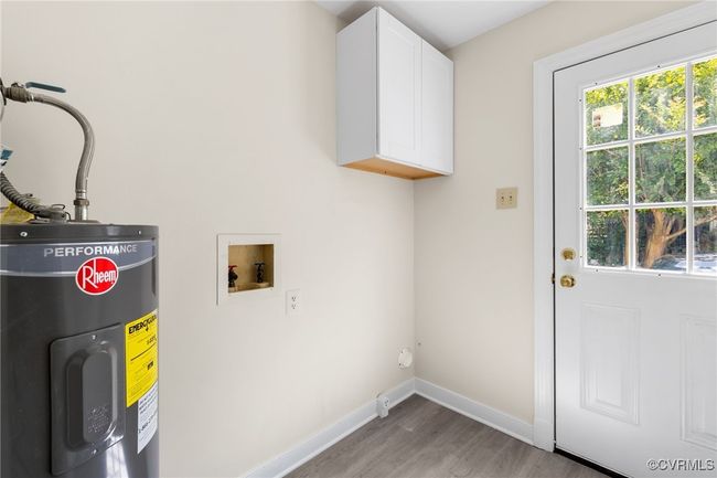 Laundry area with electric water heater, cabinet space, and washer/dryer connections. | Image 24