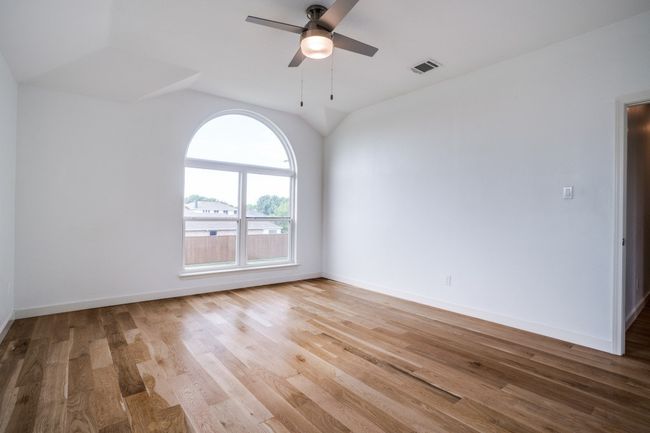 Unfurnished room featuring a ceiling fan, wood finished floors, baseboards, and vaulted ceiling | Image 26