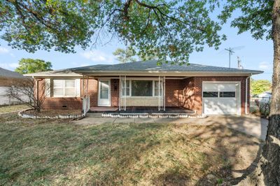 Ranch-style home with a porch, a front lawn, and a garage | Image 2