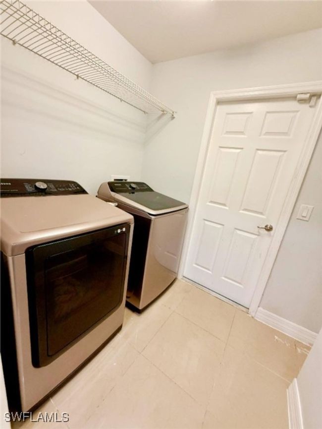 Washroom with light tile patterned floors, separate washer and dryer, and laundry area | Image 26