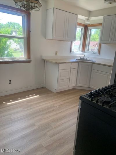 Kitchen with a notable chandelier, stainless steel range with gas cooktop, white cabinets, and light hardwood / wood-style floors | Image 3