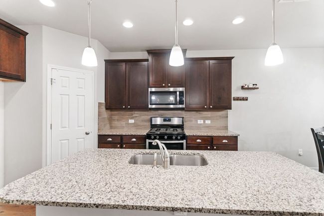 Kitchen featuring an island with sink, a sink, backsplash, and appliances with stainless steel finishes | Image 19