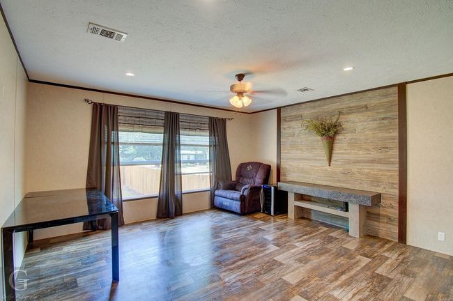 Unfurnished room with wood finished floors, a textured ceiling, crown molding, a fireplace, and recessed lighting | Image 8