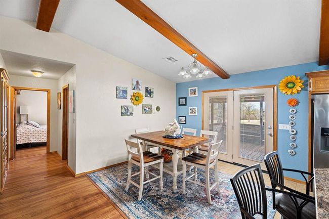 Dining space featuring an inviting chandelier, baseboards, light wood-style floors, visible vents, and vaulted ceiling with beams | Image 22