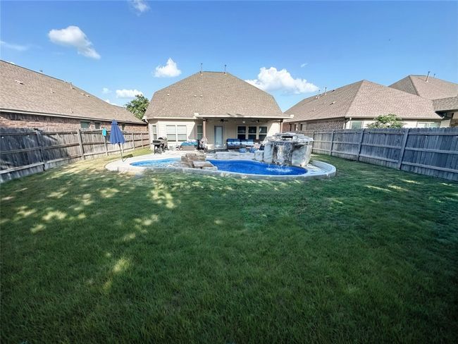 Back of property featuring a fenced backyard, pool with two waterfalls, and a patio area | Image 31