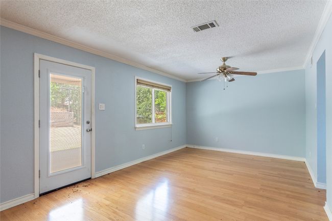 Empty room with light wood-style floors, ornamental molding, a ceiling fan, baseboards, and a textured ceiling | Image 12