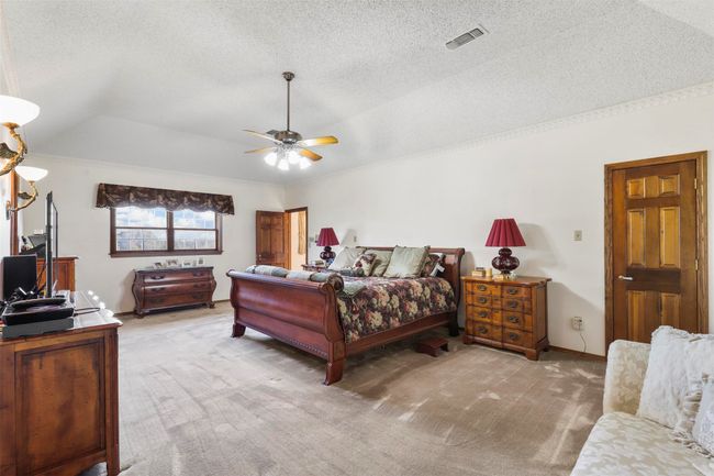 Bedroom featuring ceiling fan, a textured ceiling, light carpet, and vaulted ceiling | Image 25