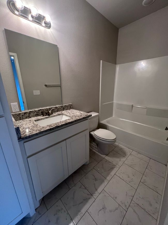 Bathroom featuring marble finish floors, toilet, vanity, and bathtub / shower combination | Image 7