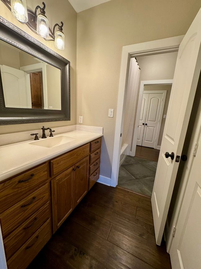 Full bathroom featuring baseboards, wood finished floors, vanity, and shower / bath combo | Image 18