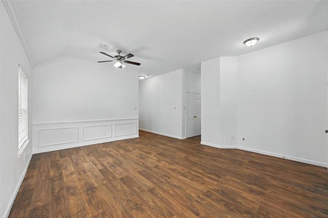 Empty room featuring ornamental molding, ceiling fan, lofted ceiling, wood finished floors, and baseboards | Image 5