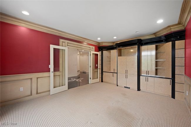 Unfurnished office with decorative walls, crown molding, carpet, wainscoting, french doors and built-ins. | Image 7