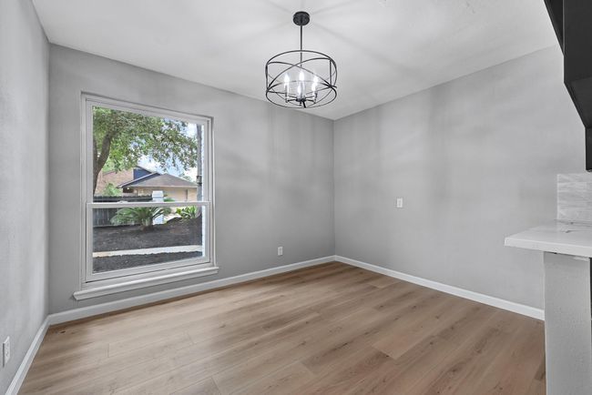 Dining area with modern chandelier – Positioned next to kitchen with large window view. | Image 20