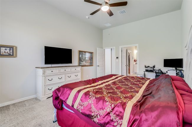 Bedroom with light colored carpet, high vaulted ceiling, baseboards, a ceiling fan, and ensuite bath | Image 22