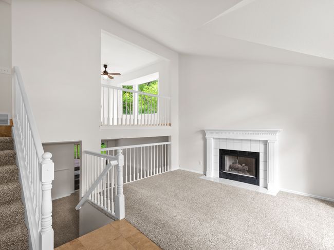 Unfurnished living room with carpet floors, lofted ceiling, a fireplace, ceiling fan, and baseboards | Image 9