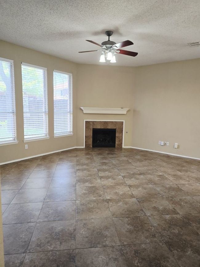 Unfurnished living room featuring a ceiling fan, baseboards, a tiled fireplace, and a textured ceiling | Image 15