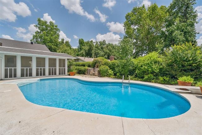 Swimming pool with a sunroom, view of scattered trees, and a patio area | Image 37