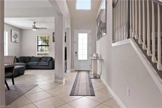 Entryway with baseboards, stairs, a ceiling fan, and light tile patterned floors | Image 5