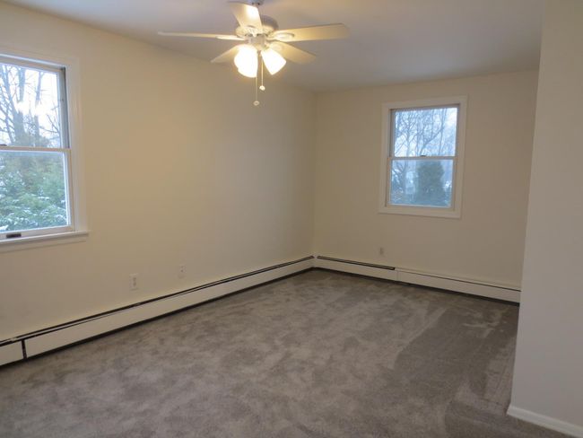 Carpeted bedroom featuring a baseboard heating unit and a ceiling fan | Image 12