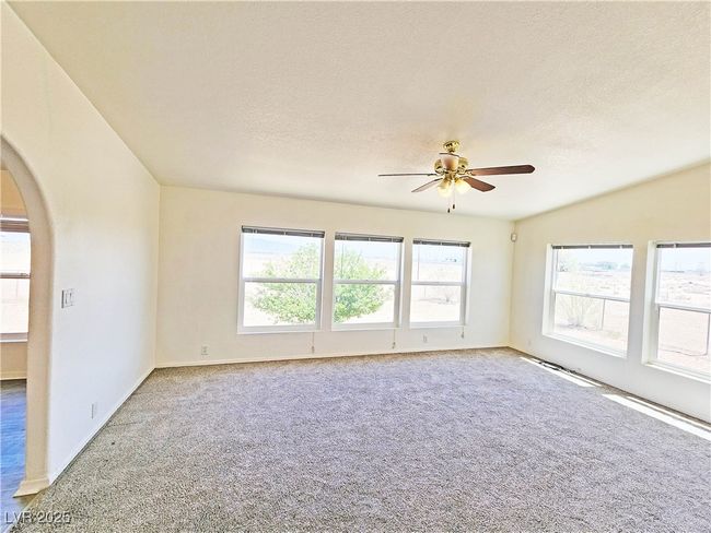 Carpeted empty room featuring arched walkways, ceiling fan, a textured ceiling, and baseboards | Image 21
