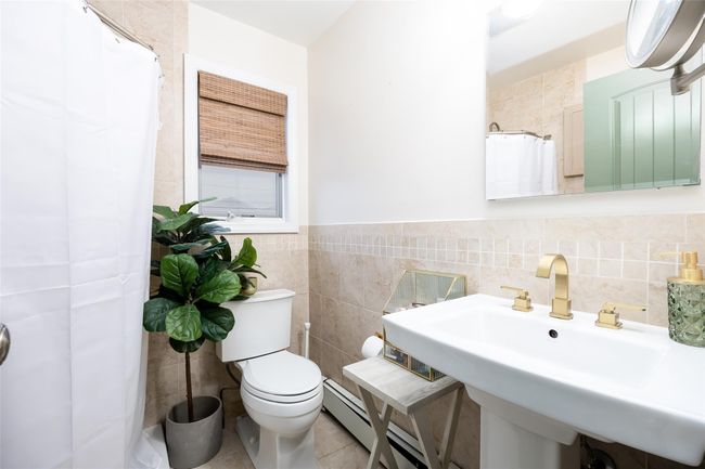 Bathroom featuring a sink, tile walls, a shower with curtain, toilet, and tile patterned flooring | Image 28