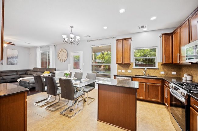 Kitchen featuring appliances with stainless steel finishes, tasteful backsplash, dark stone counters, open floor plan, and a chandelier | Image 10