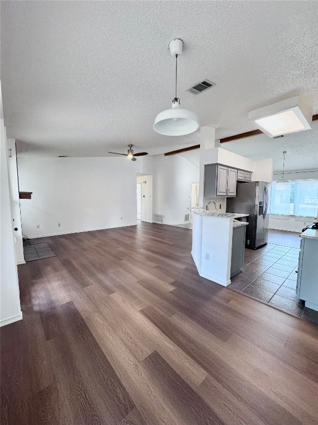 Kitchen featuring open floor plan, hanging light fixtures, a ceiling fan, a textured ceiling, and gray cabinets | Image 9