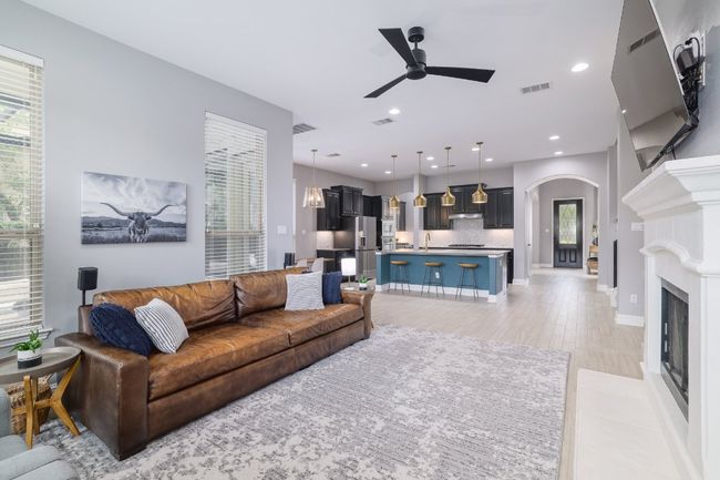Living area featuring arched walkways, a ceiling fan, healthy amount of natural light, a glass covered fireplace, and recessed lighting | Image 5