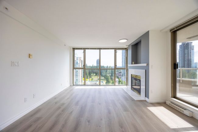 Unfurnished living room featuring expansive windows, wood finished floors, and a tile fireplace | Image 10