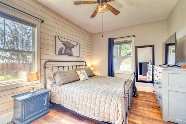Bedroom featuring wood walls, light wood-type flooring, and a ceiling fan | Image 17