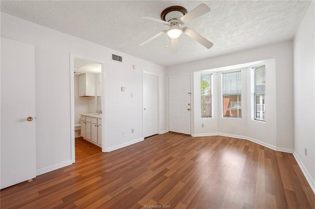 Unfurnished bedroom with a textured ceiling, light wood finished floors, a ceiling fan, and connected bathroom | Image 8