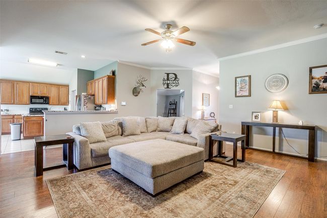 Living area with ceiling fan, light wood-style floors, and crown molding | Image 14