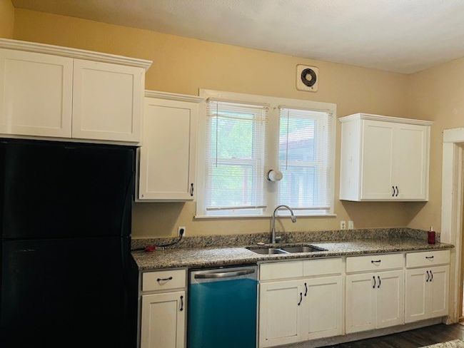 Kitchen with dishwasher, freestanding refrigerator, a sink, white cabinets, and dark wood finished floors | Image 16