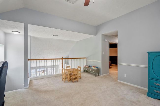 From the game room, we get a great view of the staircase and balcony railing, adding an open, airy feel to the space. Down the hallway to the right, you’ll catch a glimpse of the media room, offering a sneak peek at the entertainment possibilities in this home. | Image 24