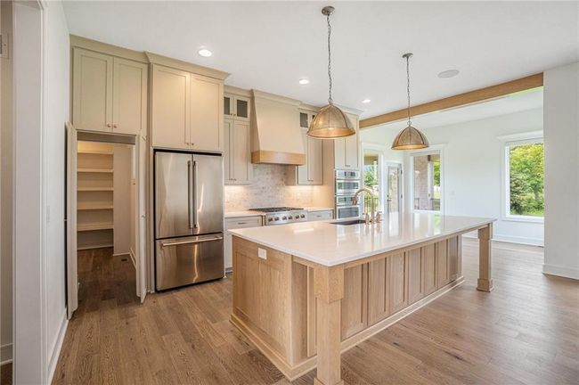 Kitchen with stainless steel appliances, custom range hood, a sink, light wood-type flooring, and recessed lighting | Image 25