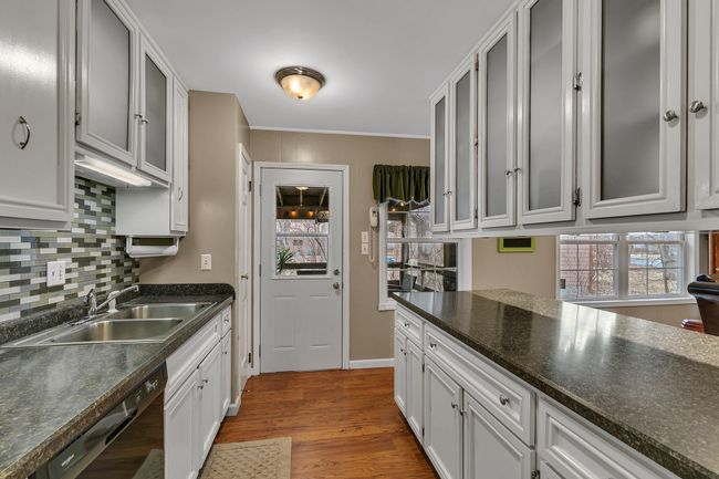 Updated kitchen boasts a tile backsplash, newer countertops, & frosted glass cabinet doors. Dishwasher, range, & microwave are only 5 years old! | Image 6
