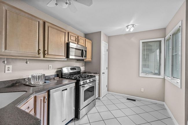 Kitchen with appliances with stainless steel finishes, light brown cabinets, dark countertops, and baseboards | Image 8