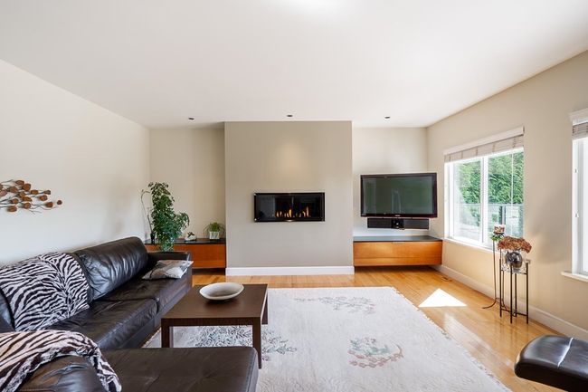 Living area with light wood-style floors and a glass covered fireplace | Image 14
