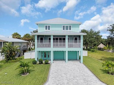 Coastal inspired home with a front lawn and a garage | Image 1