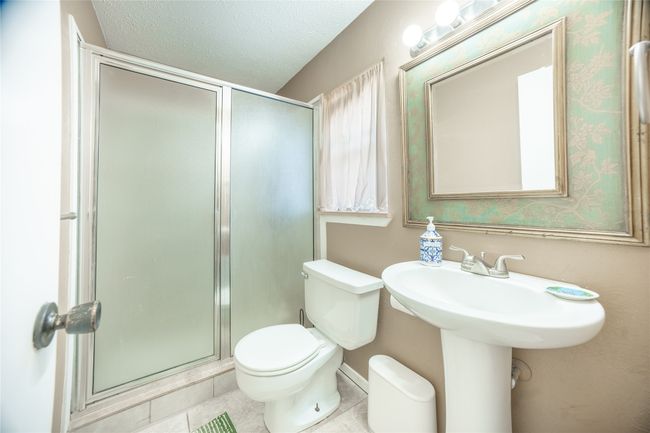Bathroom featuring tile patterned floors, toilet, a shower stall, and a textured ceiling | Image 14