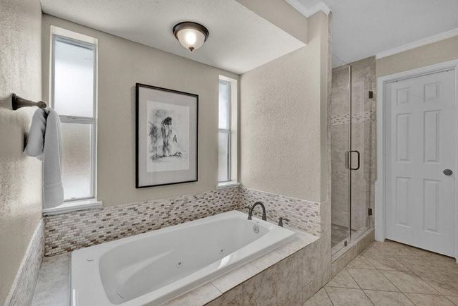 Bathroom featuring a tub with jets, tile patterned flooring, a textured wall, and a shower stall | Image 29
