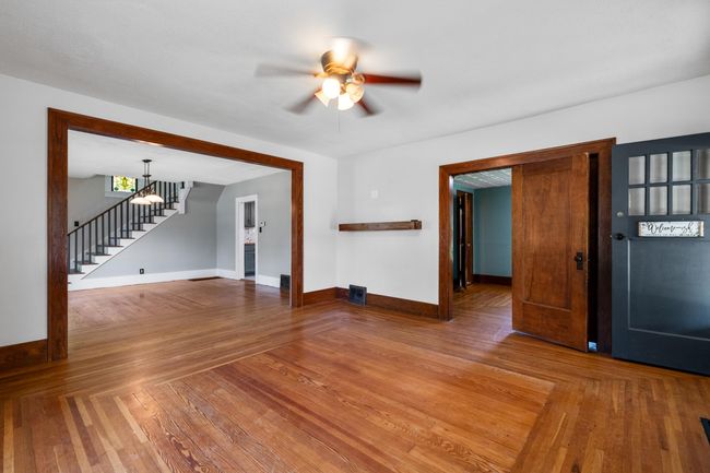 Unfurnished living room featuring stairway, a ceiling fan, baseboards, and wood finished floors | Image 5