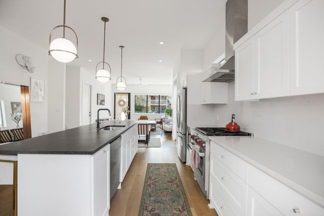 Gourmet kitchen with a long center island, a gas range stove, appliances with stainless steel finishes, and light wood finished floors | Image 8