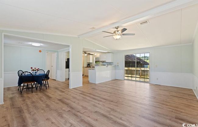 Living room with ceiling fan, light wood finished floors, a wainscoted wall, and a decorative wall | Image 8