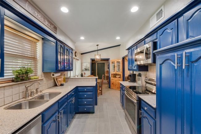 Kitchen with appliances with stainless steel finishes, a sink, blue cabinetry, tasteful backsplash, and plenty of natural light | Image 17