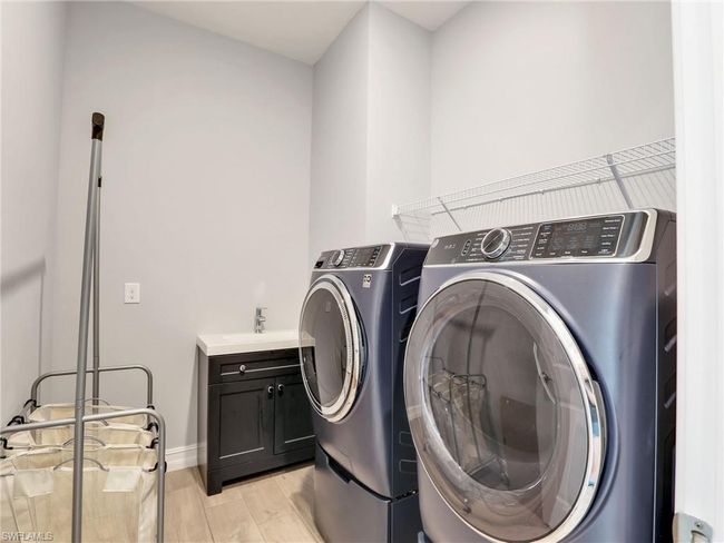 Washroom featuring separate washer and dryer, light hardwood / wood-style flooring, cabinets, and sink | Image 32