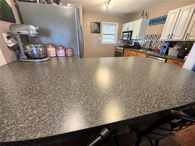 Kitchen with stainless steel appliances, breakfast bar and decorative backsplash | Image 14