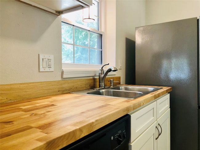 Kitchen with wood counters, freestanding refrigerator, white cabinetry, and dishwasher | Image 11