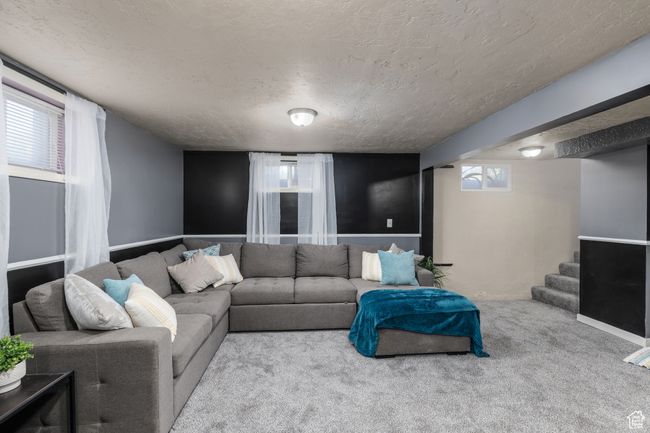 Living room featuring a textured ceiling, new carpet, plenty of natural light, and stairs | Image 15
