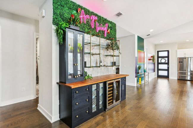 Indoor dry bar featuring stainless steel refrigerator, beverage cooler, dark wood-style floors, recessed lighting, and lofted ceiling | Image 32